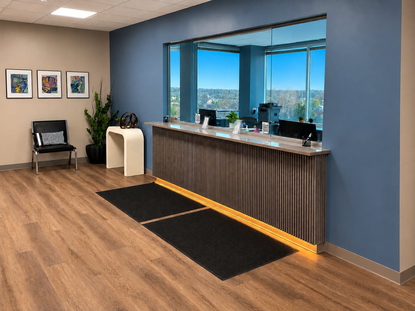 Lott Behavioral Health reception desk with large windows, a chair, plants, and framed artwork.